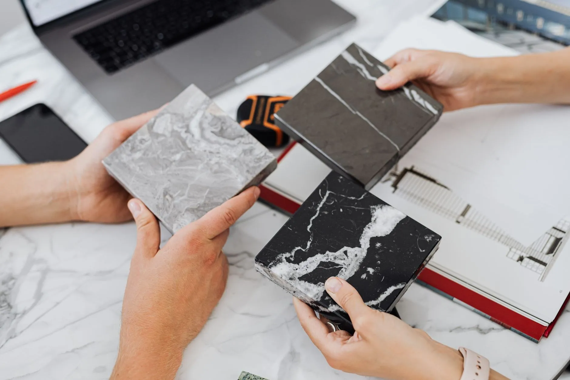 Two architects comparing material samples over drawings on a desk while specifying finishes for a commercial interior lighting project