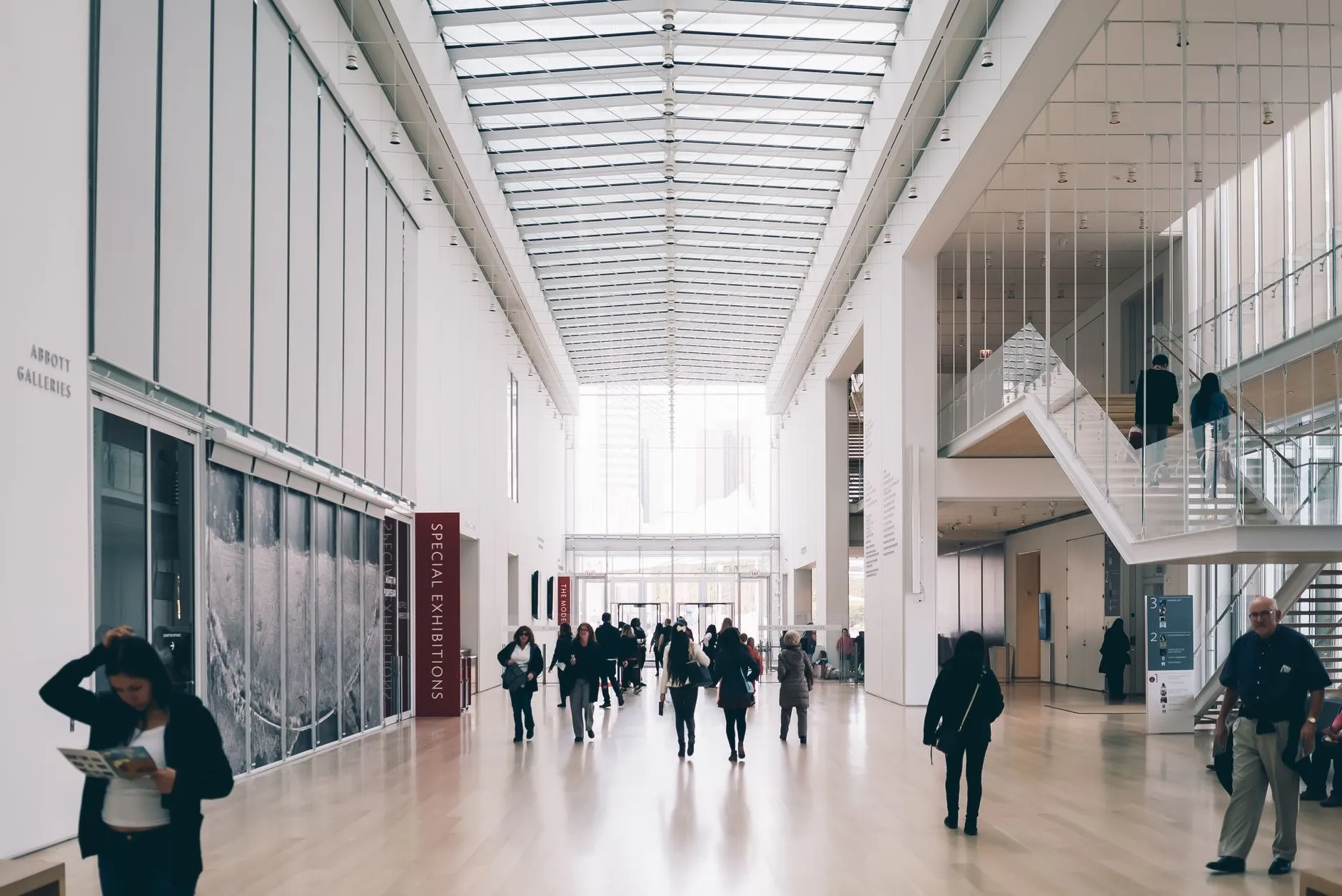 Art gallery atrium with linear ceiling lighting and hanging track-mounted projectors over a public circulation space