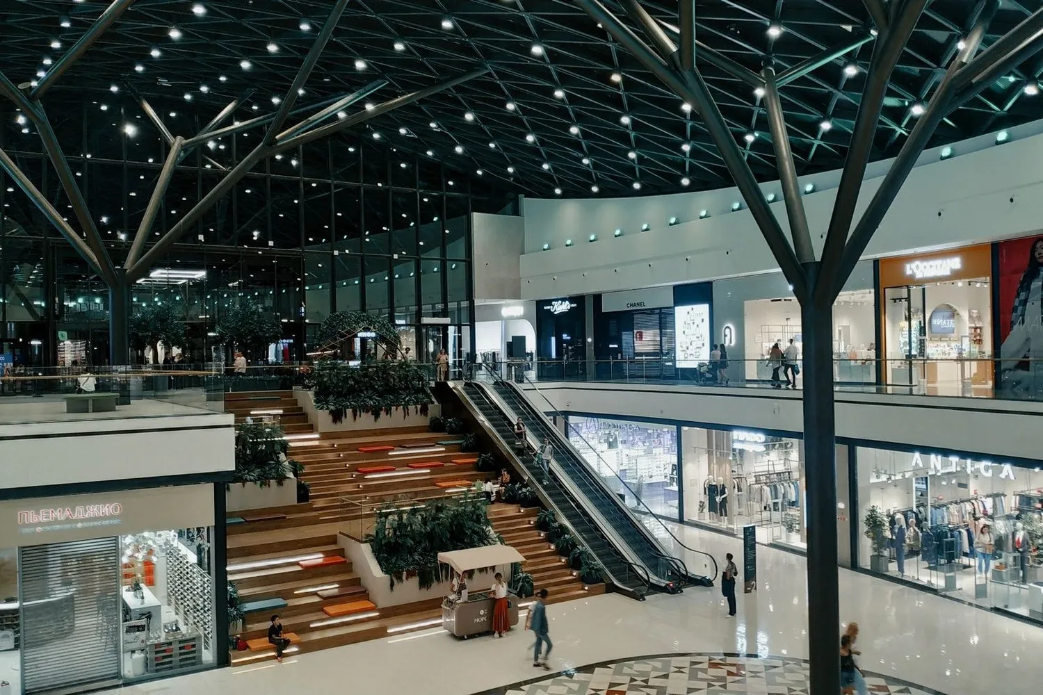 A multi-storey shopping mall atrium lit by hundreds of commercial LED downlights and spotlights in the ceiling grid — commercial lighting manufacturer project reference