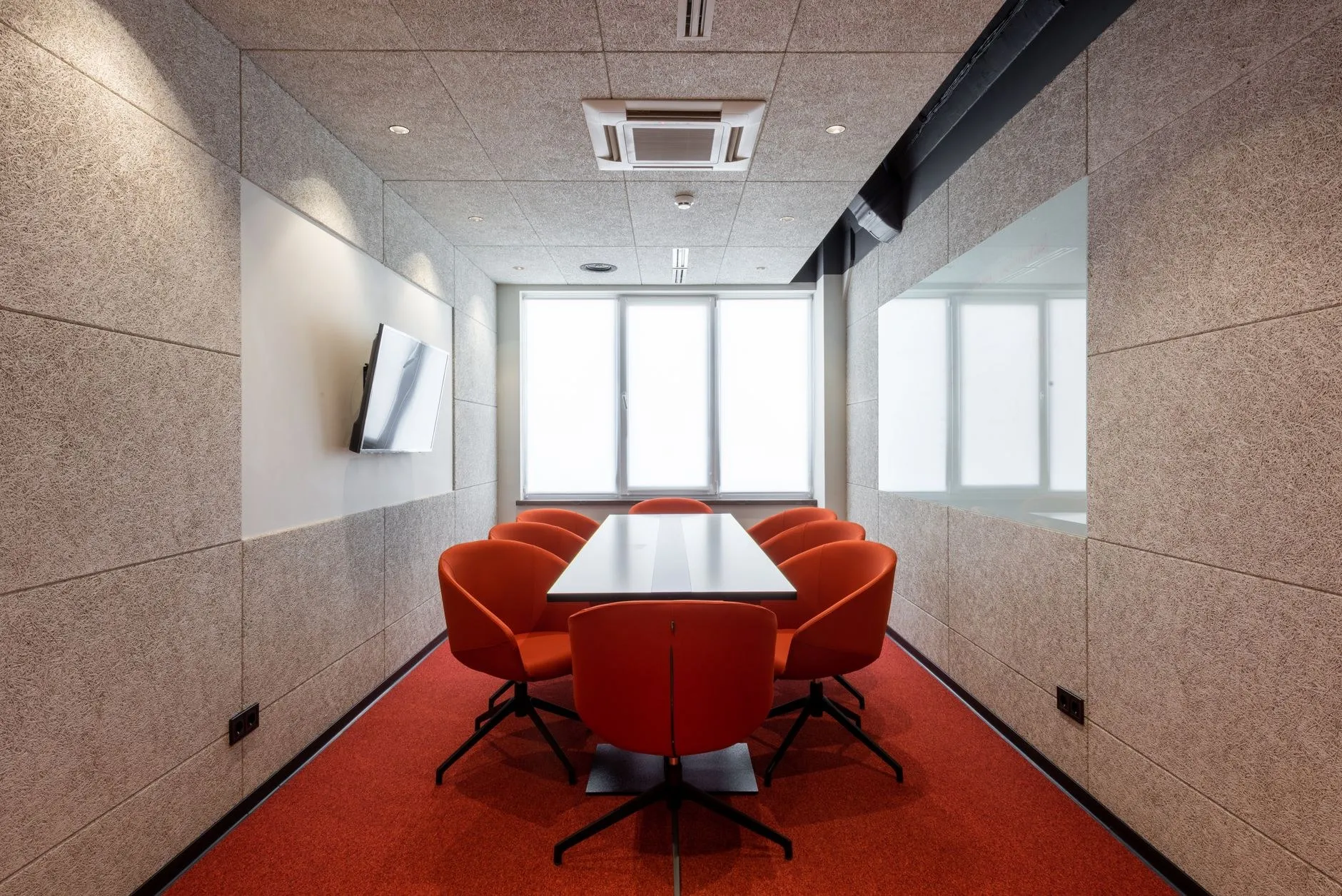 Modern conference room with linear and recessed commercial lighting above a meeting table, showing a workplace lighting specification