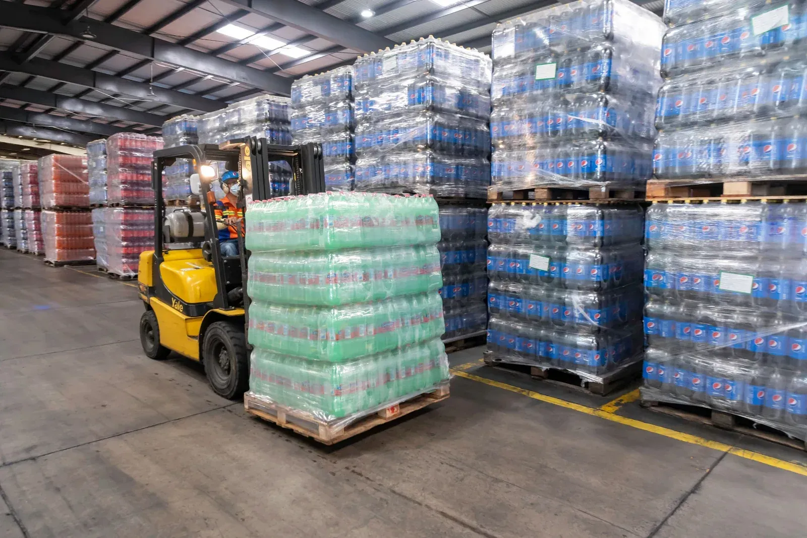 Forklift moving shrink-wrapped pallets of cartons in an export warehouse, the freight stage of a downlight order shipped from a China factory