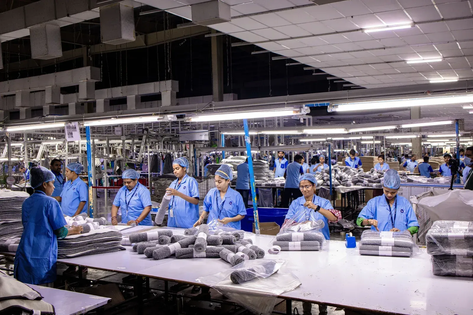 Production line operators assembling light fixtures in a factory, the mass-production stage of an ODM downlight programme