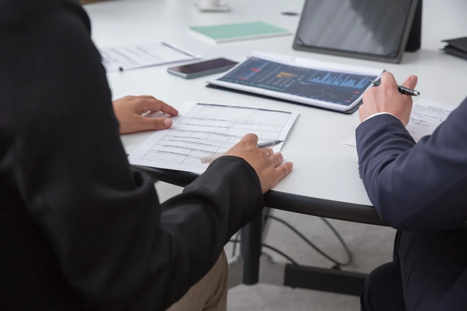 Buyers and an engineer reviewing specification documents and a tablet across a meeting table, the moment an ODM downlight requirement list is agreed