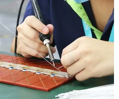 ENCORE operator soldering LED boards on a production bench during downlight assembly, an in-house light-engine process