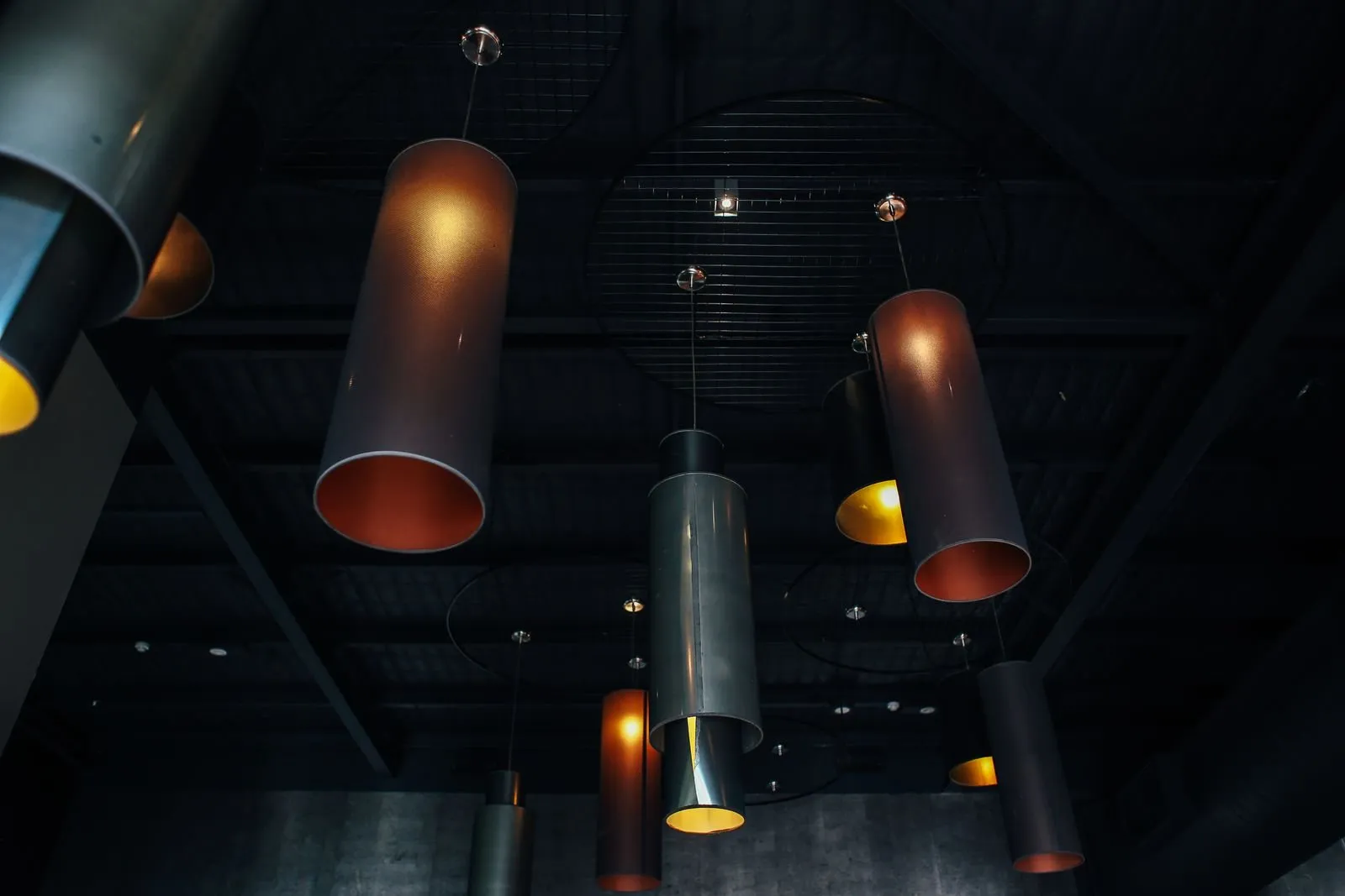 ETL certification lighting — moody track and pendant spotlights on a dark commercial ceiling, where certified safe lighting fixtures are installed
