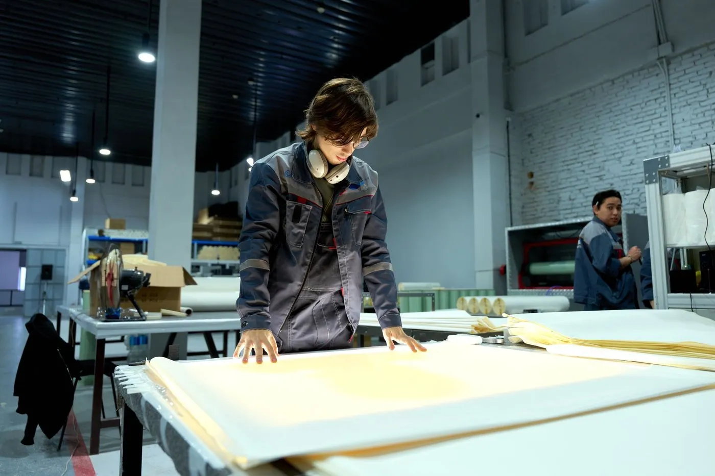 LED lighting factory inspection — a quality inspector checking finished fixtures on a workbench inside a clean, modern lighting factory
