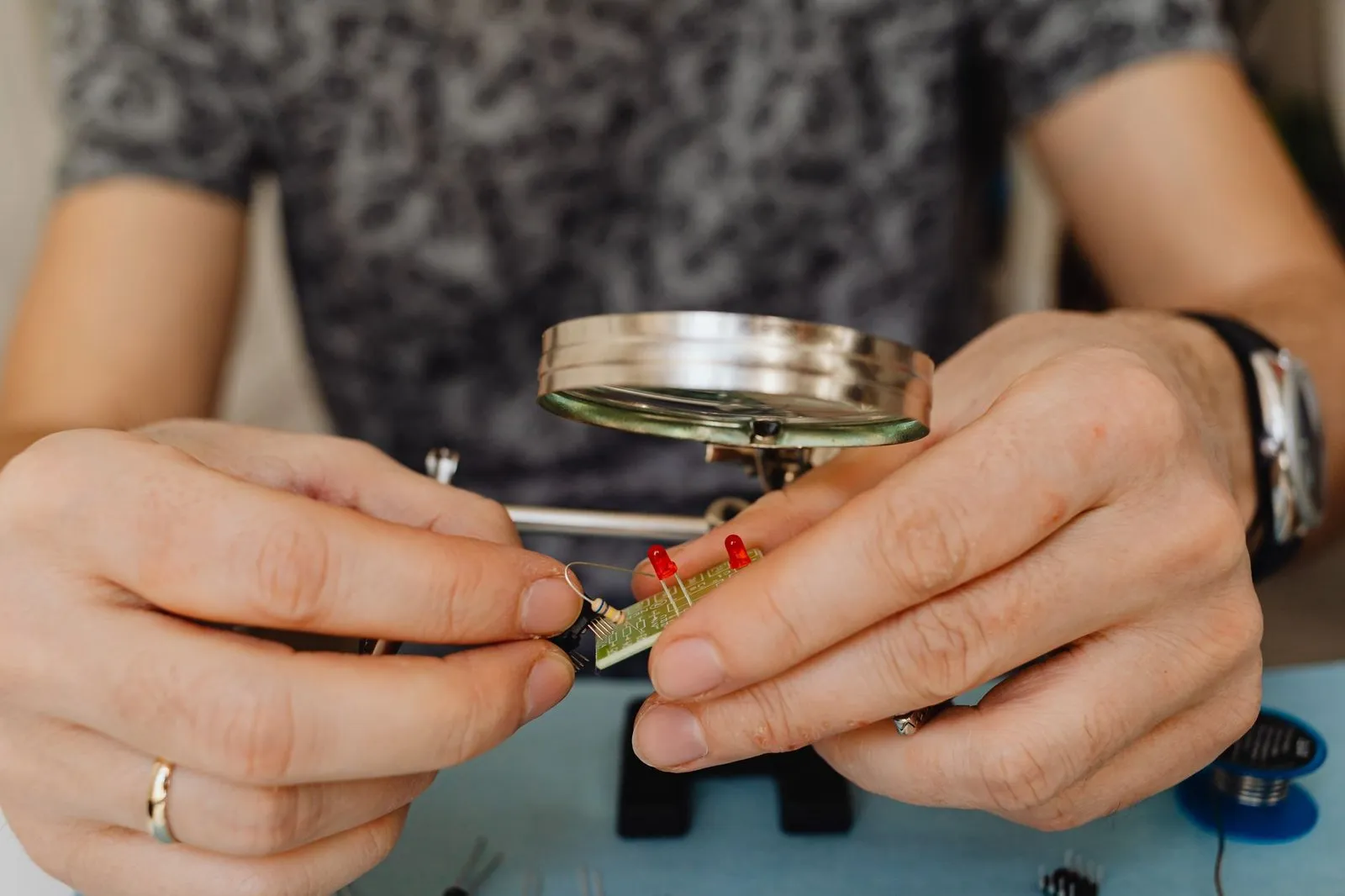 Close-up of a technician assembling and testing a light fixture module by hand at a workbench, the manual operation that a small custom batch still has to absorb