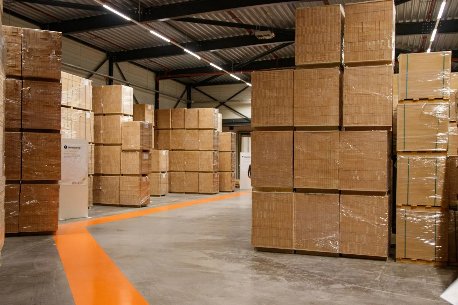 Cartons stacked and wrapped on pallets in a warehouse aisle, staged for dispatch of a custom LED track lighting order