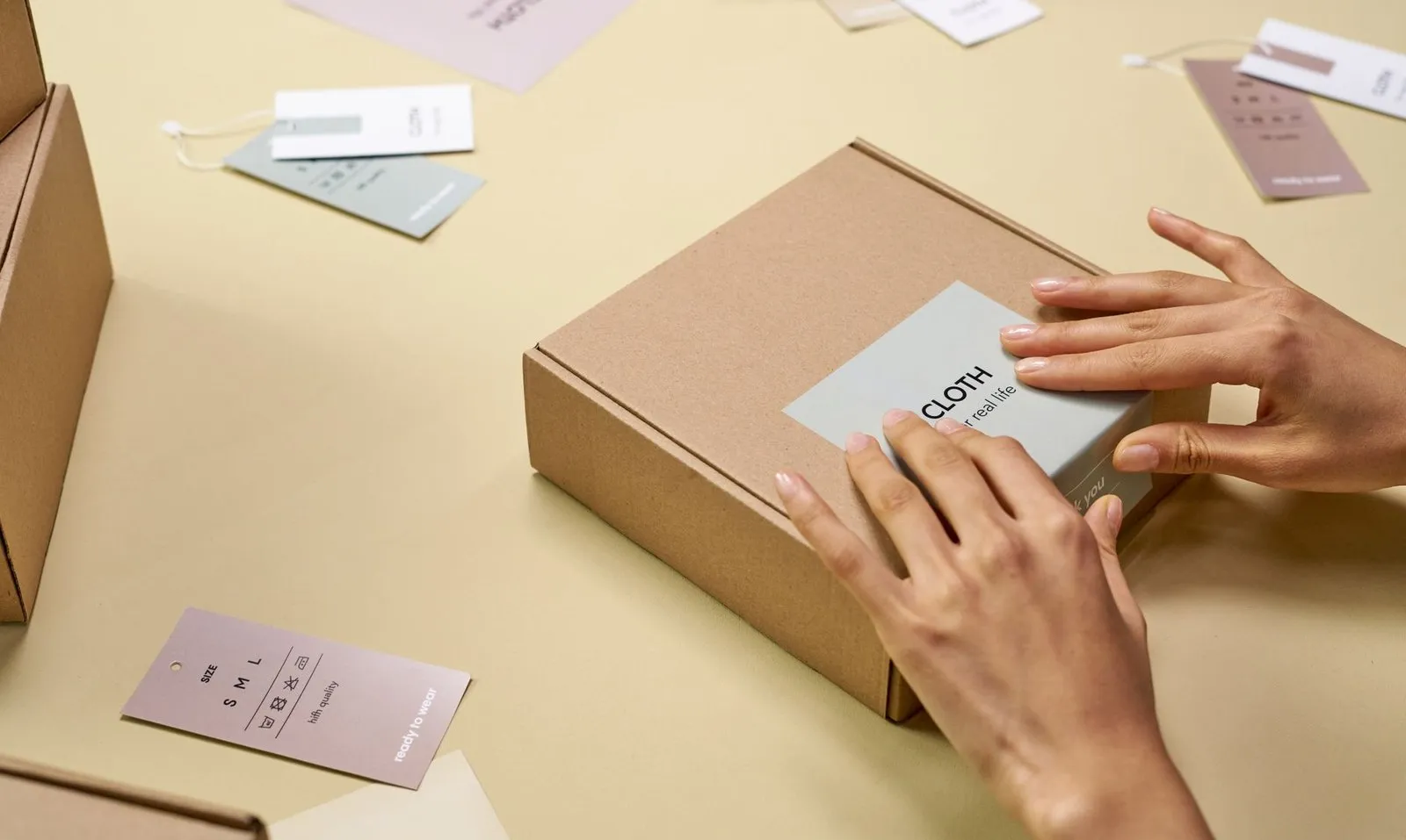 Hands applying a printed brand label to a plain shipping carton — the branding and packaging customization that a 100 unit LED track lighting order can reach without new tooling