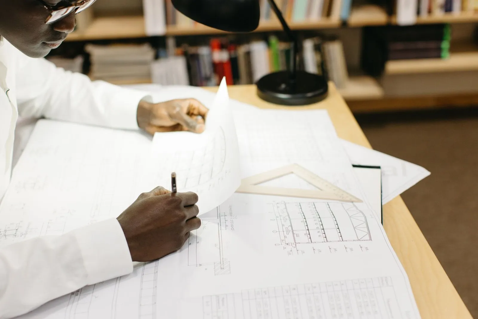Engineer working through a technical drawing and specification sheet by hand, the document set behind a custom LED track lighting RFQ and its three price breaks