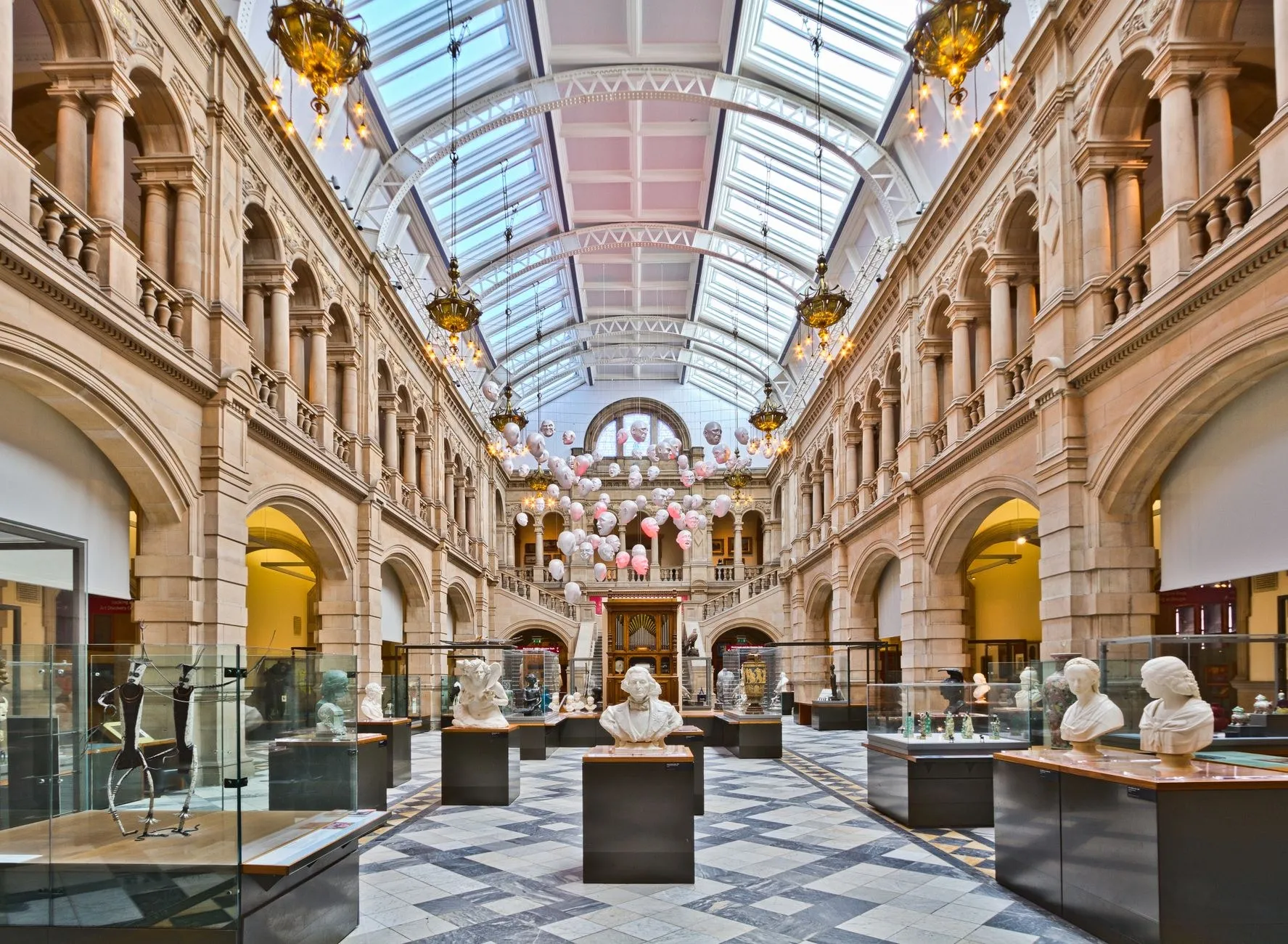 Museum gallery interior with sculptures lit by precise ceiling-mounted commercial spotlights and daylight from above