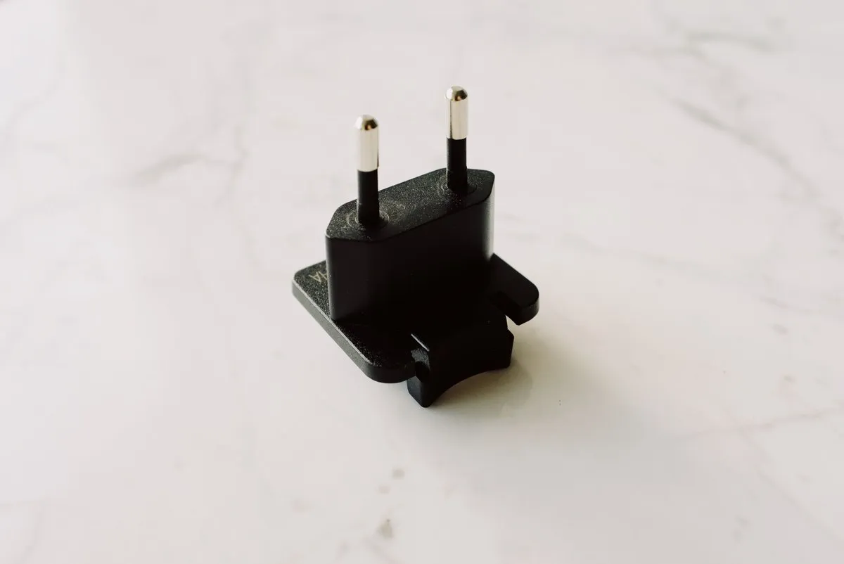 Close up of a black power supply adapter body on a marble surface showing the moulded housing and cord exit