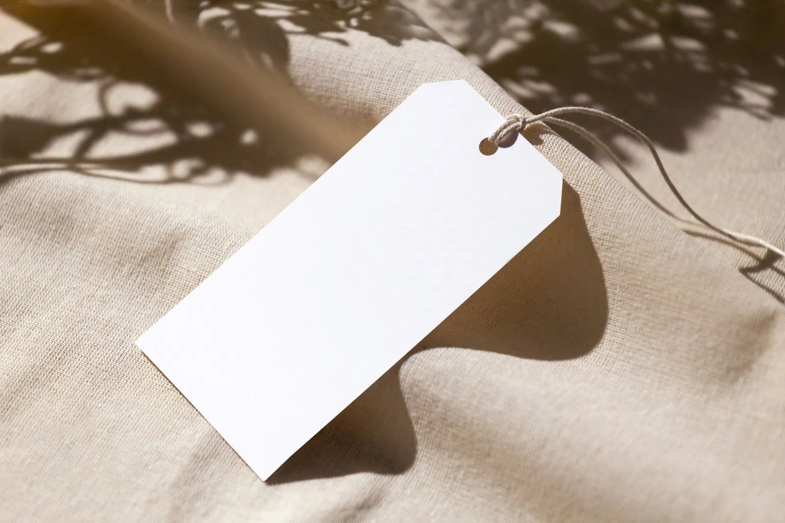 Blank private label lighting hang tags resting on natural fabric, ready to carry a buyer's own brand name