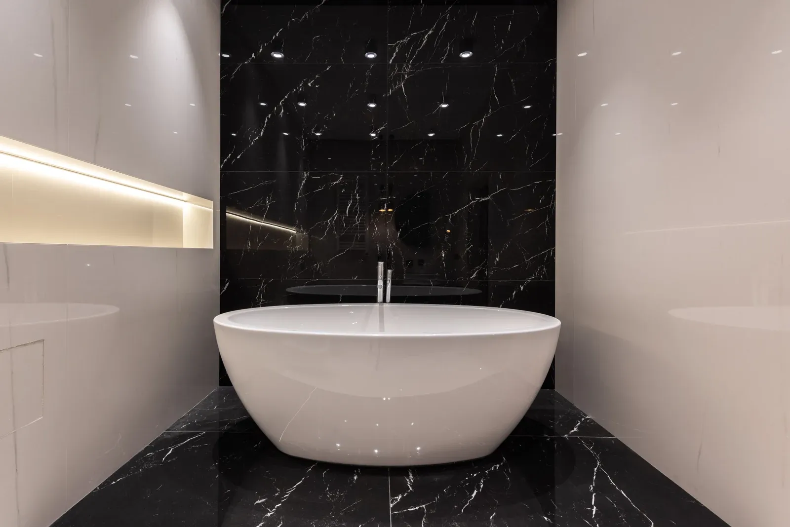 Modern bathroom with an IP-rated recessed downlight above a freestanding bath, showing a wet-zone application where the sealed gasket changes the tooling
