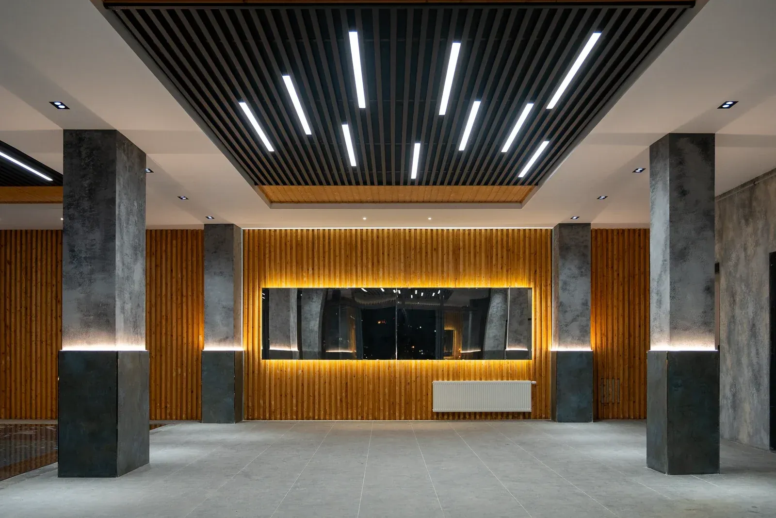 Hotel lobby ceiling with linear and recessed lighting integrated into a slatted timber soffit, an architectural specification where the cut-out is set by the design team