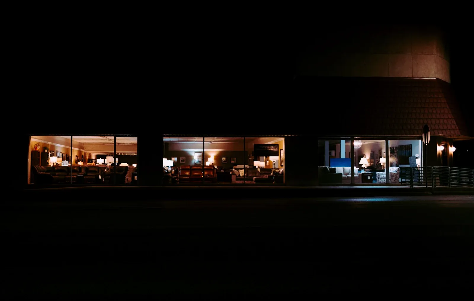 Retail showroom interior lit at night through a glazed shopfront, an application where CRI and R9 on a recessed downlight decide how merchandise reads