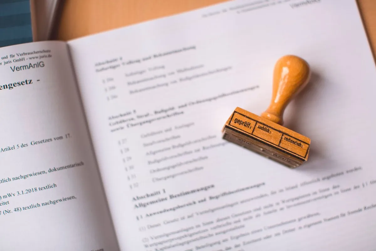 Compliance documentation on a desk with a wooden stamp, representing the certificate file an SAA approved accessory order has to carry
