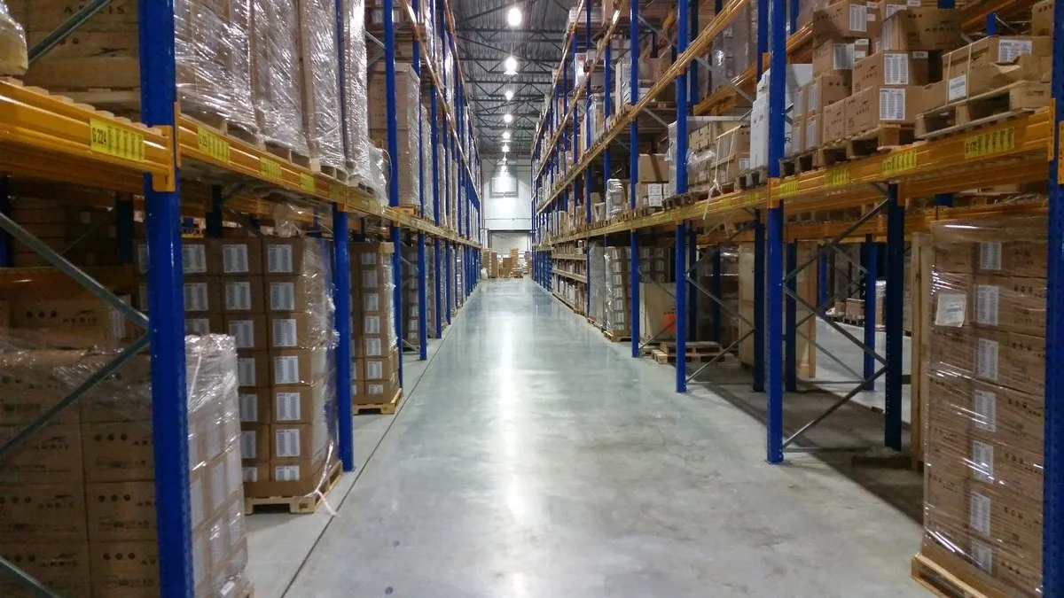 Warehouse aisle with pallet racking and cartons waiting for compliance clearance before an Australian accessory order is released