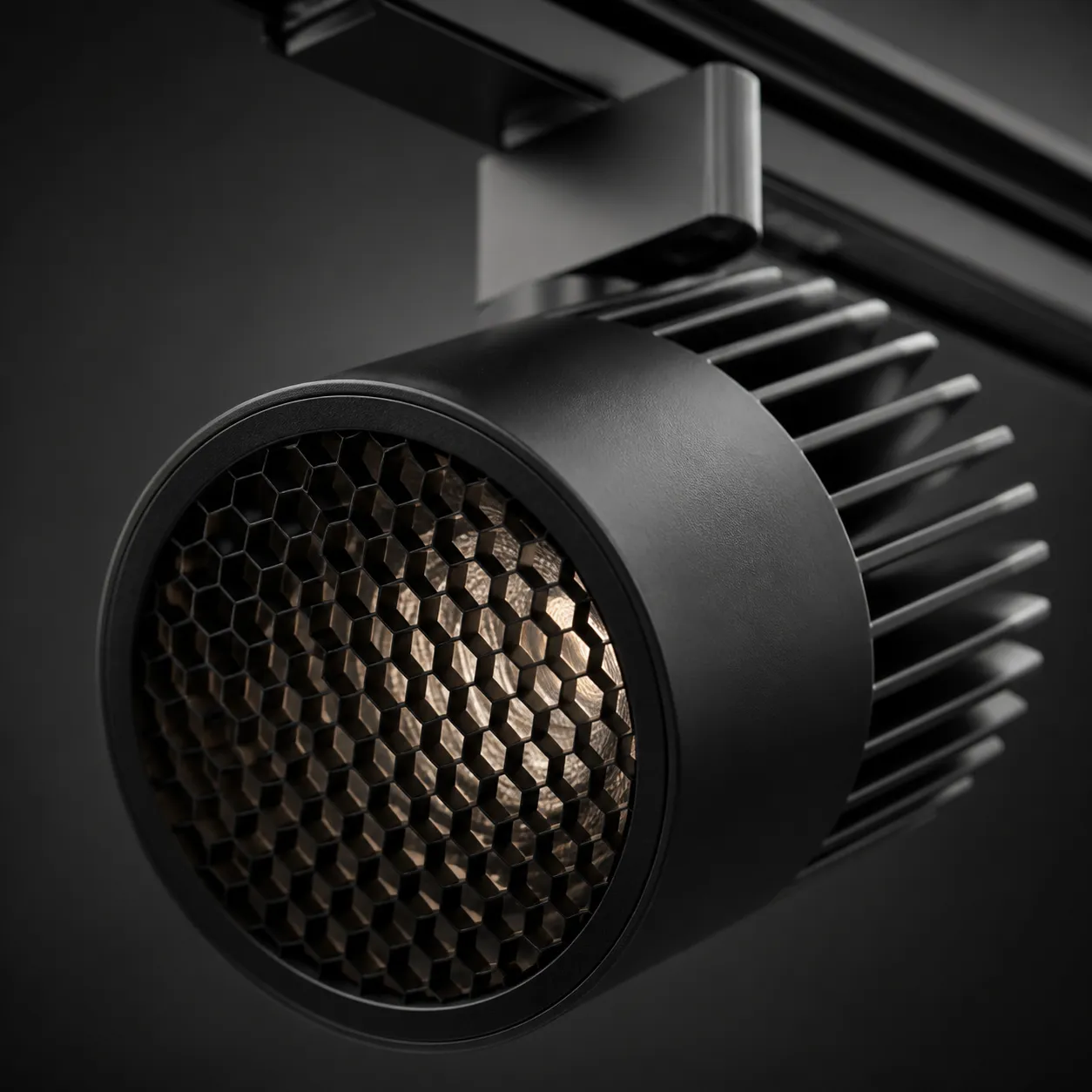 Close-up of a matte black LED track head with an anti-glare honeycomb louver and heat-sink fins.