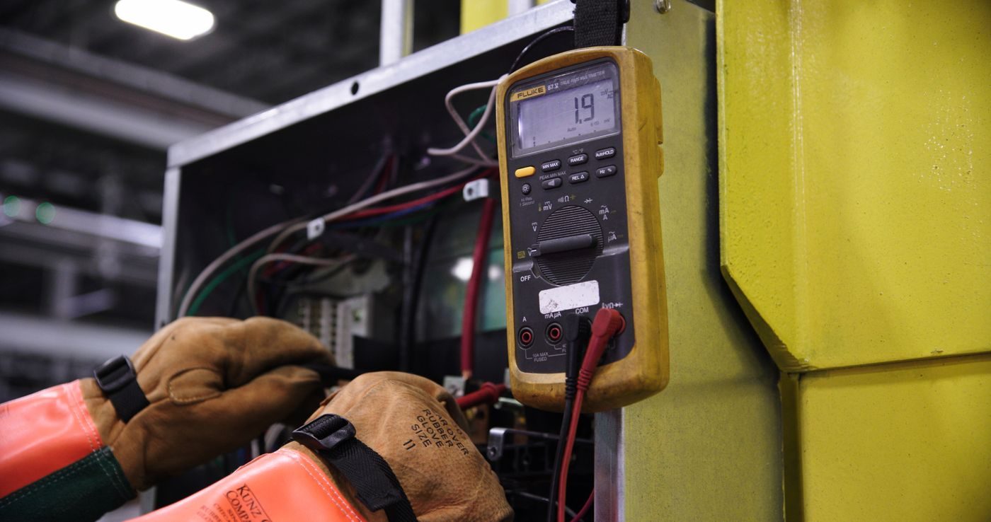 ETL electrical safety testing — a technician checks a panel with a digital multimeter during certification verification