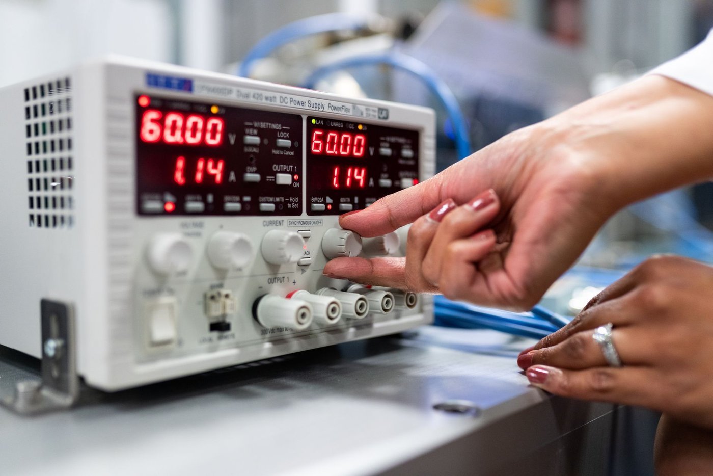 A close-up of a calibrated power supply unit being set during an electrical verification test in a lighting laboratory