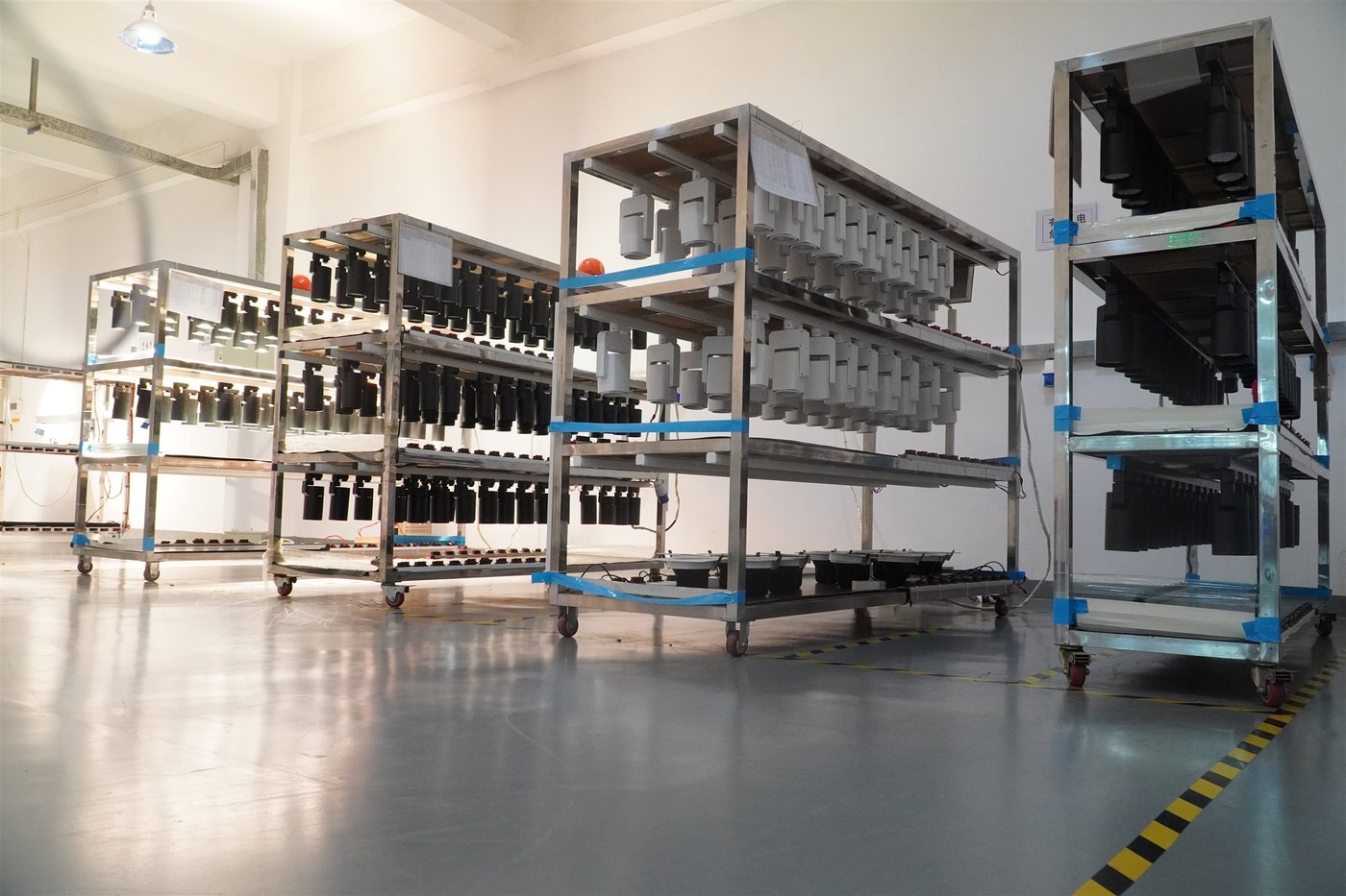 Rows of LED track fixtures running on an ENCORE aging rack before packing