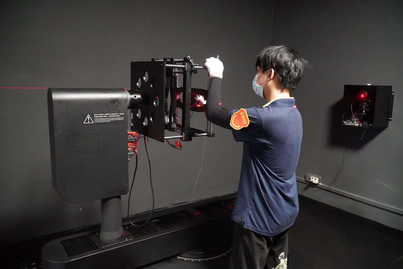 A technician in an ENCORE dark room positioning a luminaire on an integrating sphere for photometric testing