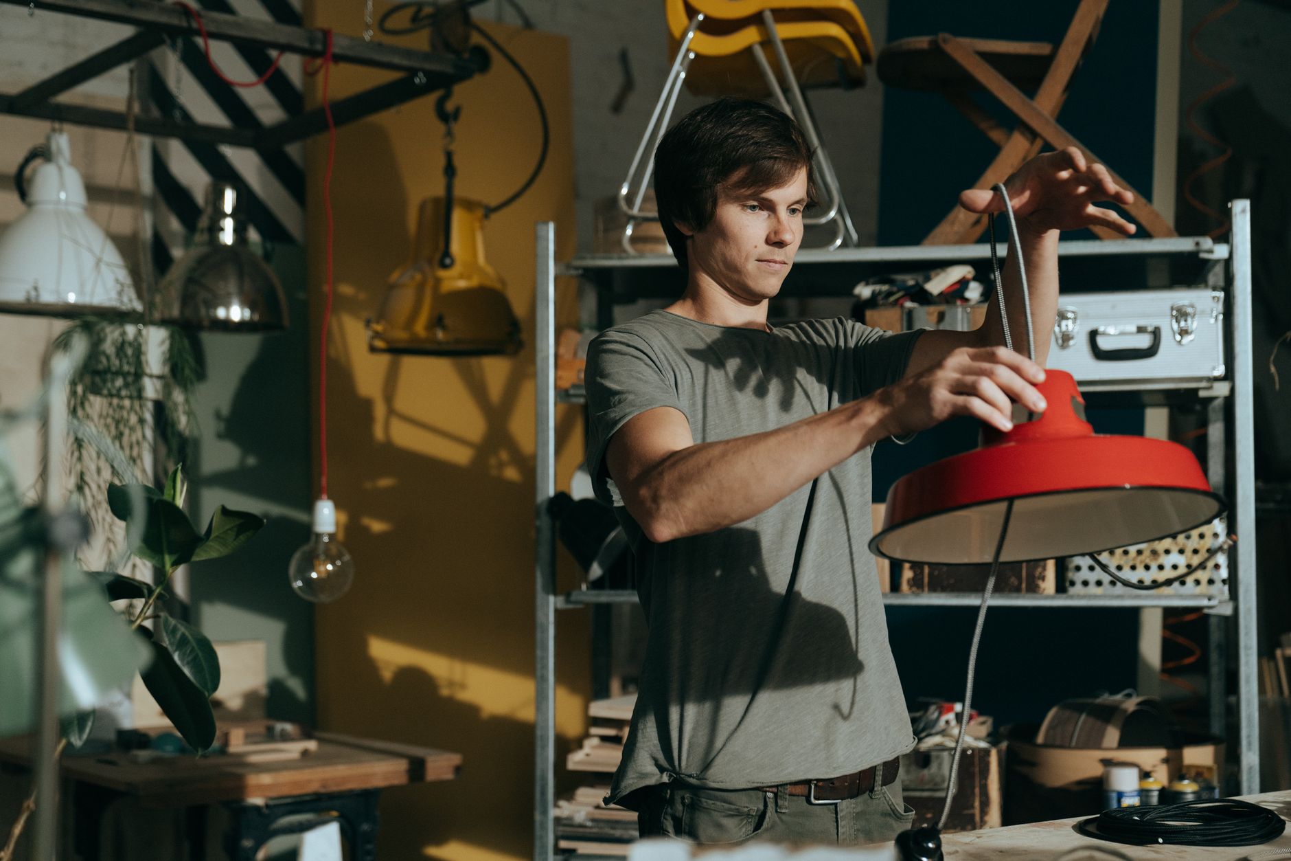 A craftsman reworking a fixture in a lighting workshop — the kind of real manufacturing and finishing work a private label lighting manufacturer does before a product ships