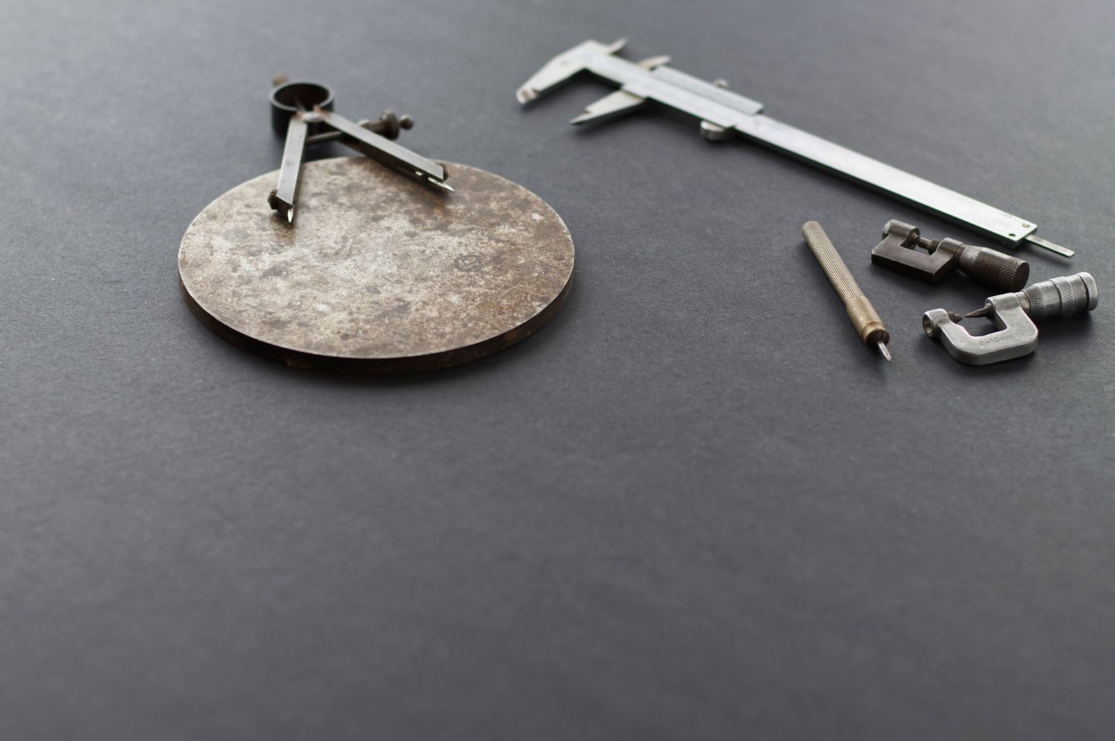Precision measuring tools including calipers and a micrometer on a dark work surface — the kind of measurement a first-article inspection records and keeps
